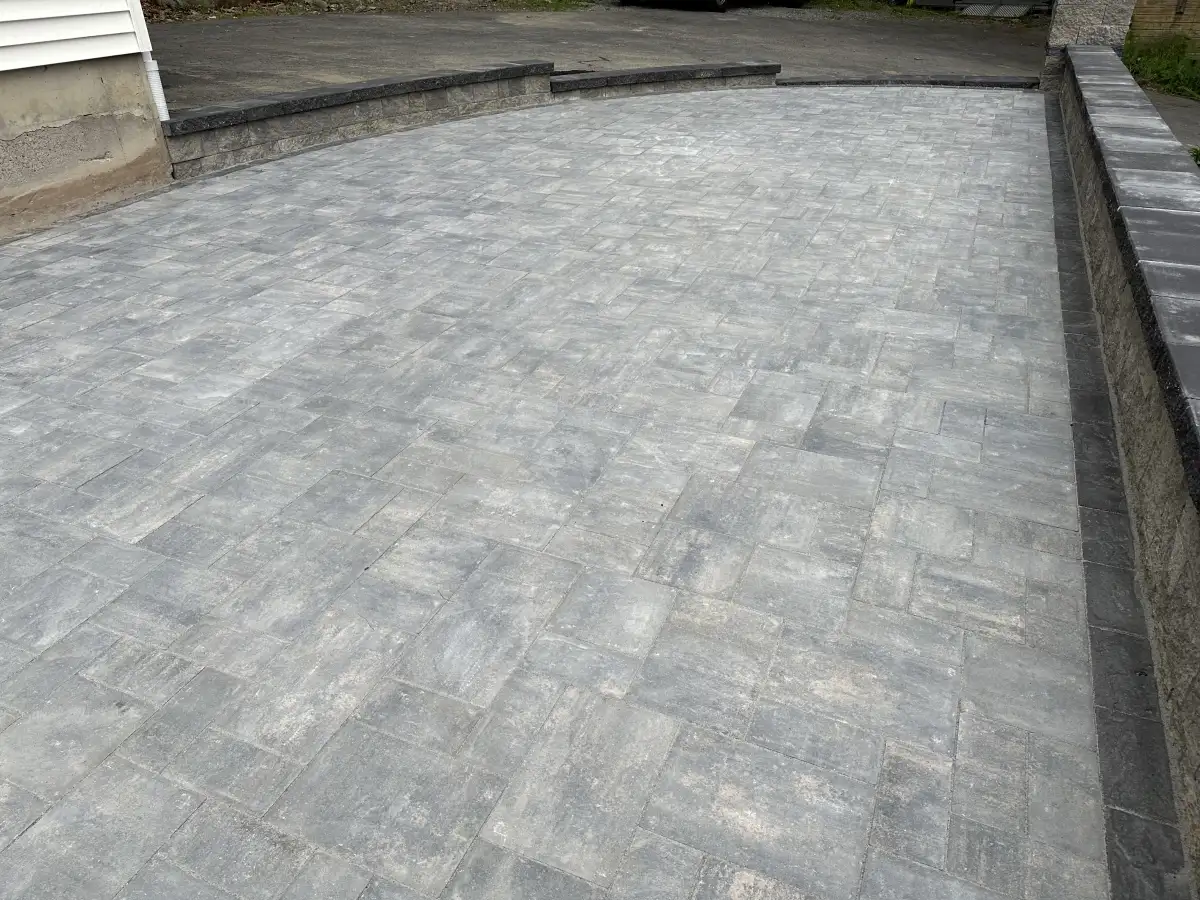 Gray paver patio with a dark contrasting border beside a home