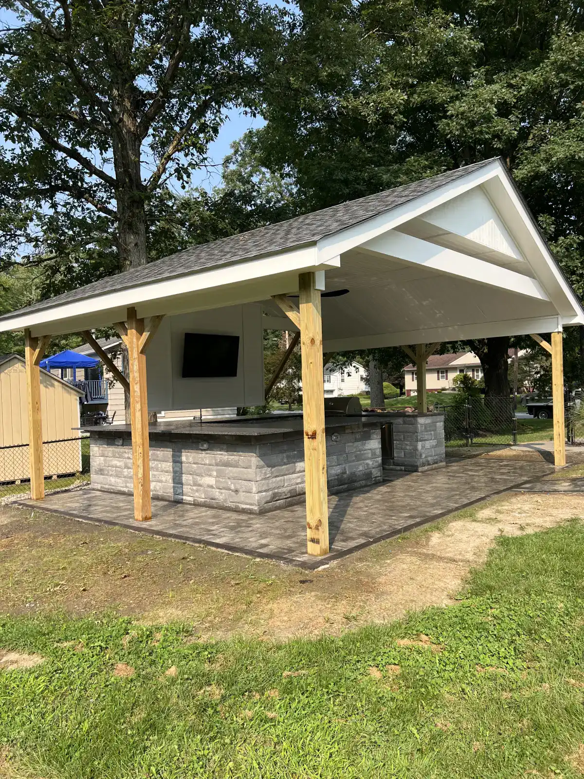 Covered outdoor kitchen and grill island on a paver patio