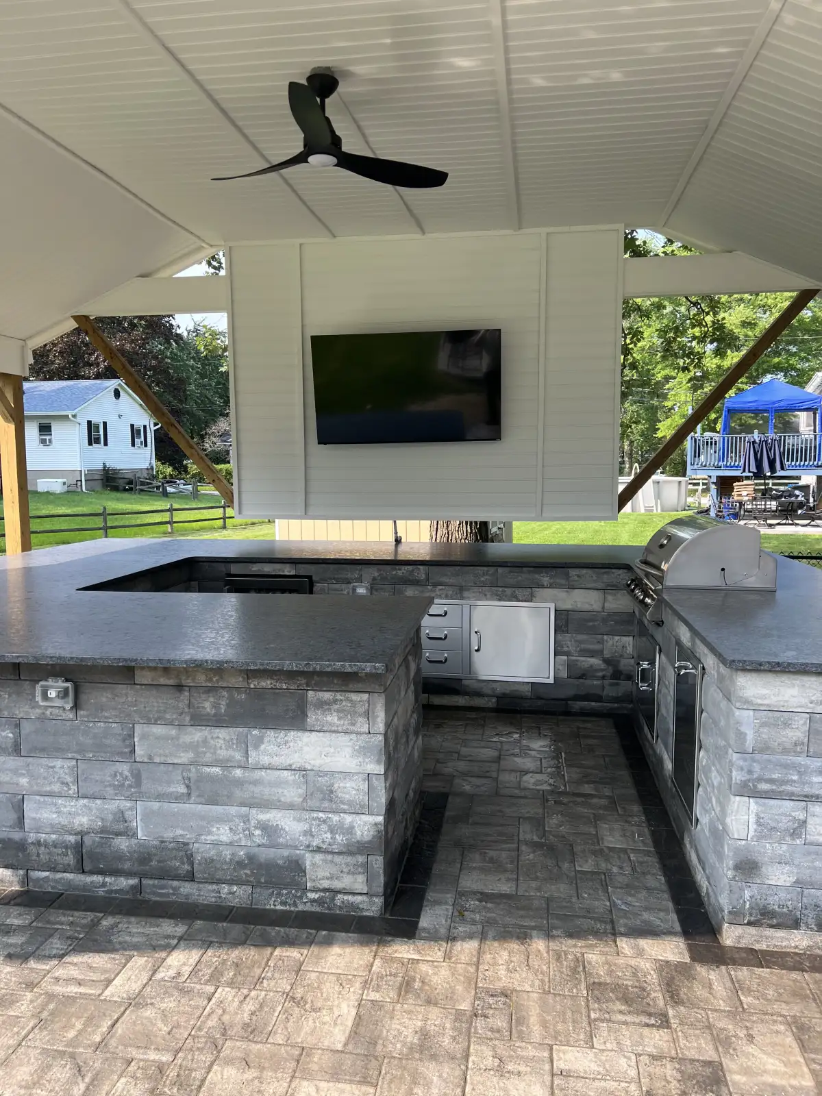 Covered outdoor kitchen with counters, built-in grill, and storage