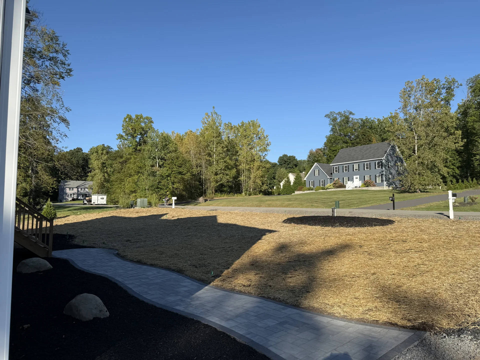 Completed new construction landscaping with paver walkway, mulch beds, and decorative boulders