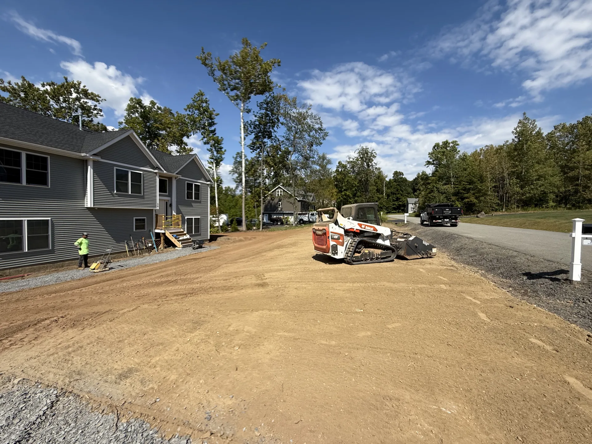 Bobcat skid steer grading a yard for new lawn installation at a residential property